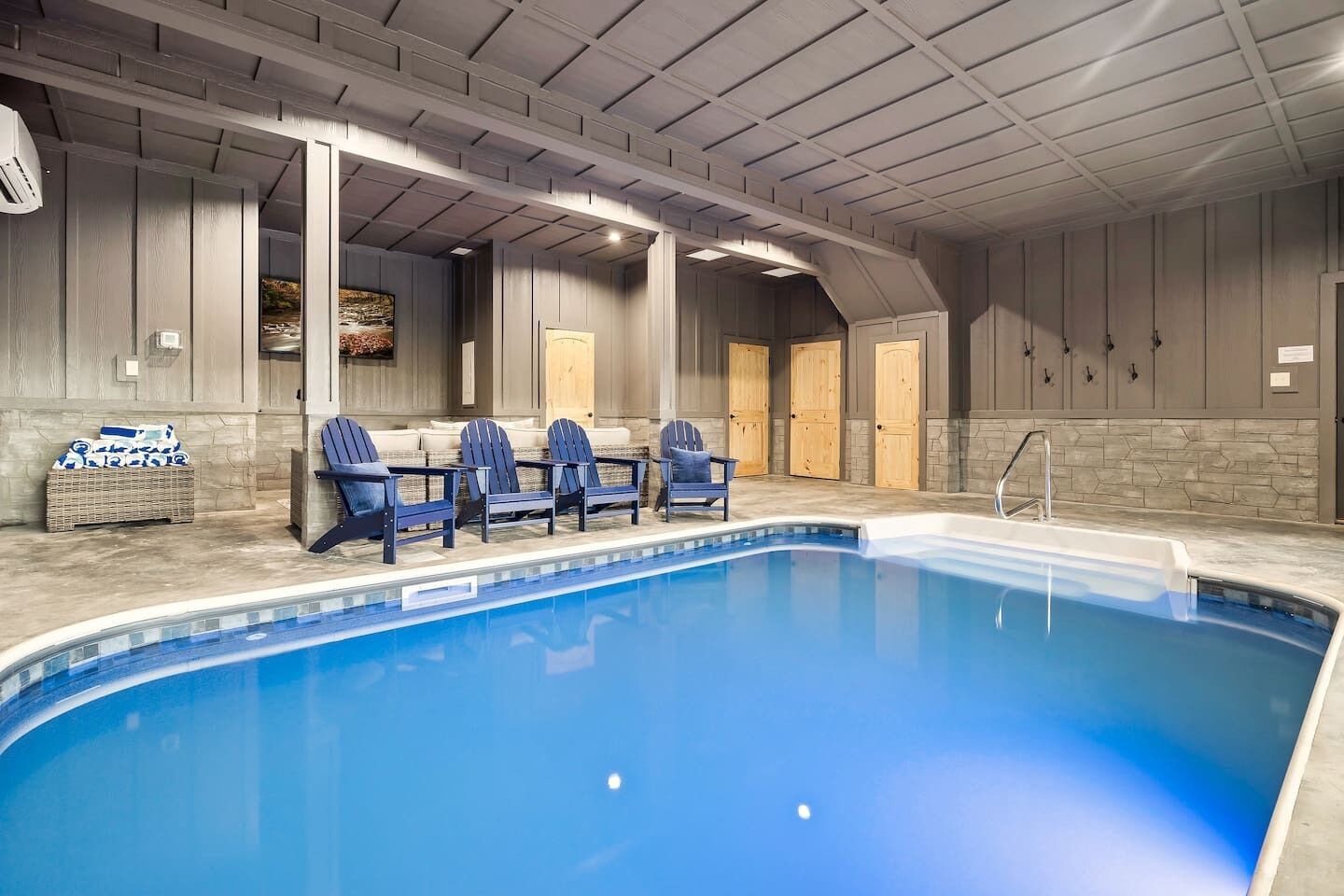 Una piscina interior con agua azul, rodeada de paredes de madera y un techo abovedado.