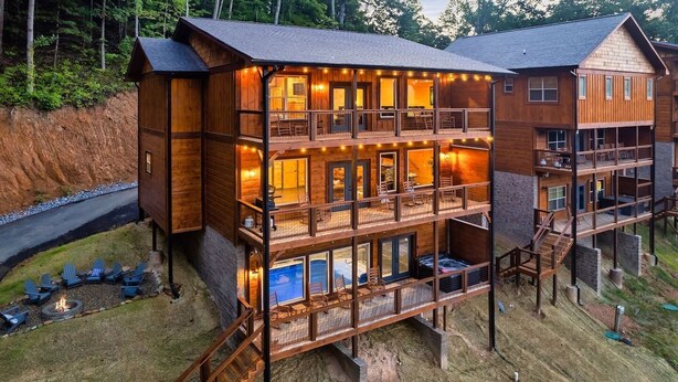 A multi-level wooden cabin with outdoor seating and a fire pit. - Private Indoor Heated Pool, Mtn Views, Hot Tub, Fire Pit, Location, Fast Wifi (Sevierville)