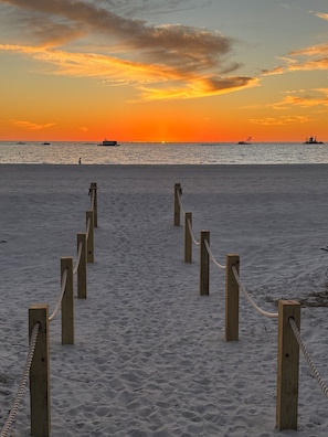 A sandy beach with wooden posts and ropes, leading to the water.