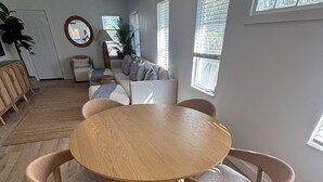 Un comedor con una mesa redonda de madera y sillas de mimbre, un sofá y un ventilador de techo.