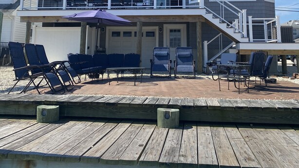 Une maison à deux étages dotée d’un balcon, d’un espace salon extérieur et d’une terrasse en bois.