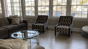 Un salon spacieux doté d’une grande fenêtre, d’un ventilateur de plafond et d’une table basse en verre.
