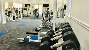 Ett gym med olika typer av träningsutrustning, inklusive hantlar och styrketräningsmaskiner.