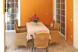 A dining area with wicker chairs and a table covered with a striped tablecloth, featuring a vase of flowers. - Apartamento Laguna with shared swimming pool (Chayofa)
