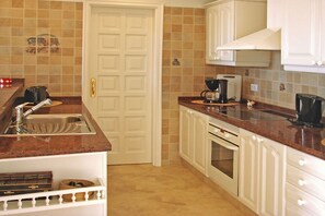 A kitchen with white cabinets, a stainless steel sink, a coffee maker, and a toaster.