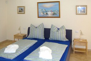 A double bed with striped bedding and pillows, two bedside tables with lamps, and framed pictures on the wall. - Apartamento Laguna with shared swimming pool (Chayofa)
