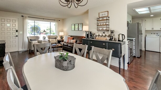 A modern kitchen with a dining area, featuring a chandelier, a coffee station, and a view of the outside. - Short Walk to Downtown, AC, Coffee Bar, Patio (Enumclaw)