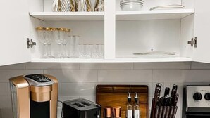 A modern kitchen with white cabinetry, a coffee maker, a toaster, and a knife block.
