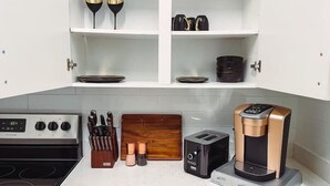 Une cuisine moderne équipée d’une cuisinière, d’un grille-pain, d’une machine à café et d’un bloc à couteaux.