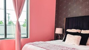 Une chambre à coucher avec un lit, une table de chevet, une lampe et une fenêtre avec des rideaux.
