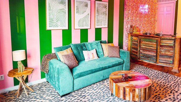 Et værelse med en teal farvet sofa, en tæppe med et mønster og et træbord.