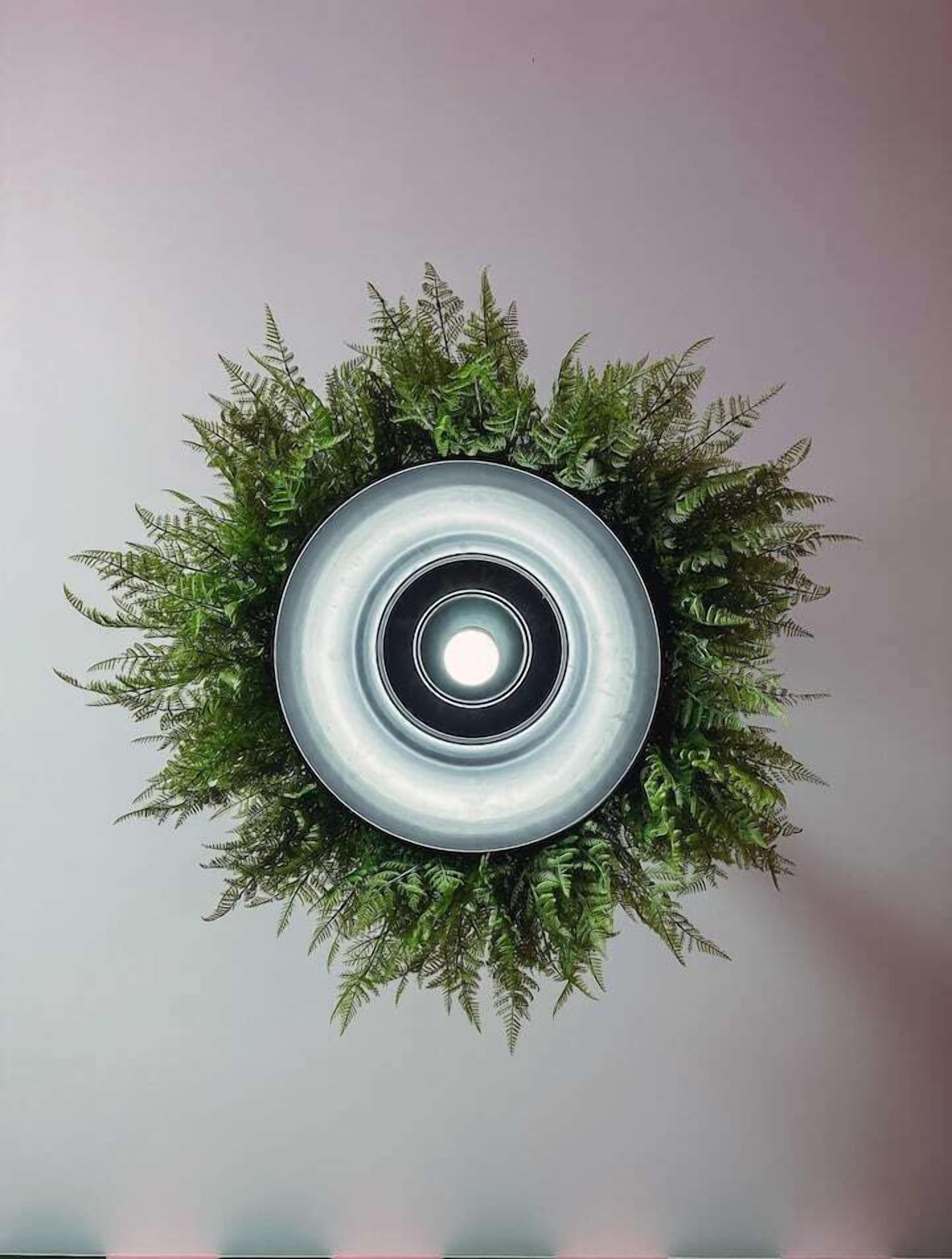 Una luminaria circular rodeada de follaje verde artificial.