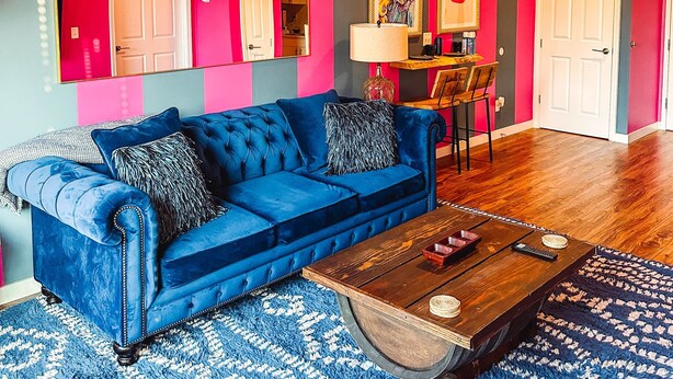 Uma sala de estar vibrante com um sofá azul, uma mesa de centro de madeira e um tapete estampado.