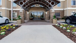A hotel entrance with a covered walkway, stone facade, and potted plants. - Equipped Studio | Top Location, Gym Access + Pool (Gulf Shores)