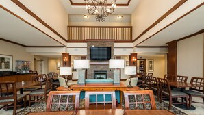 A spacious dining area with wooden tables and chairs, a central fireplace, and a television above it. - Equipped Studio | Top Location, Gym Access + Pool (Gulf Shores)