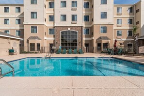 A swimming pool with lounge chairs and a building with multiple balconies and windows. - Equipped Studio | Top Location, Gym Access + Pool (Gulf Shores)