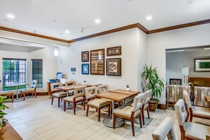 A spacious dining area with multiple tables and chairs, framed artwork on the walls, and a large window providing natural light. - Equipped Studio | Top Location, Gym Access + Pool (Gulf Shores)