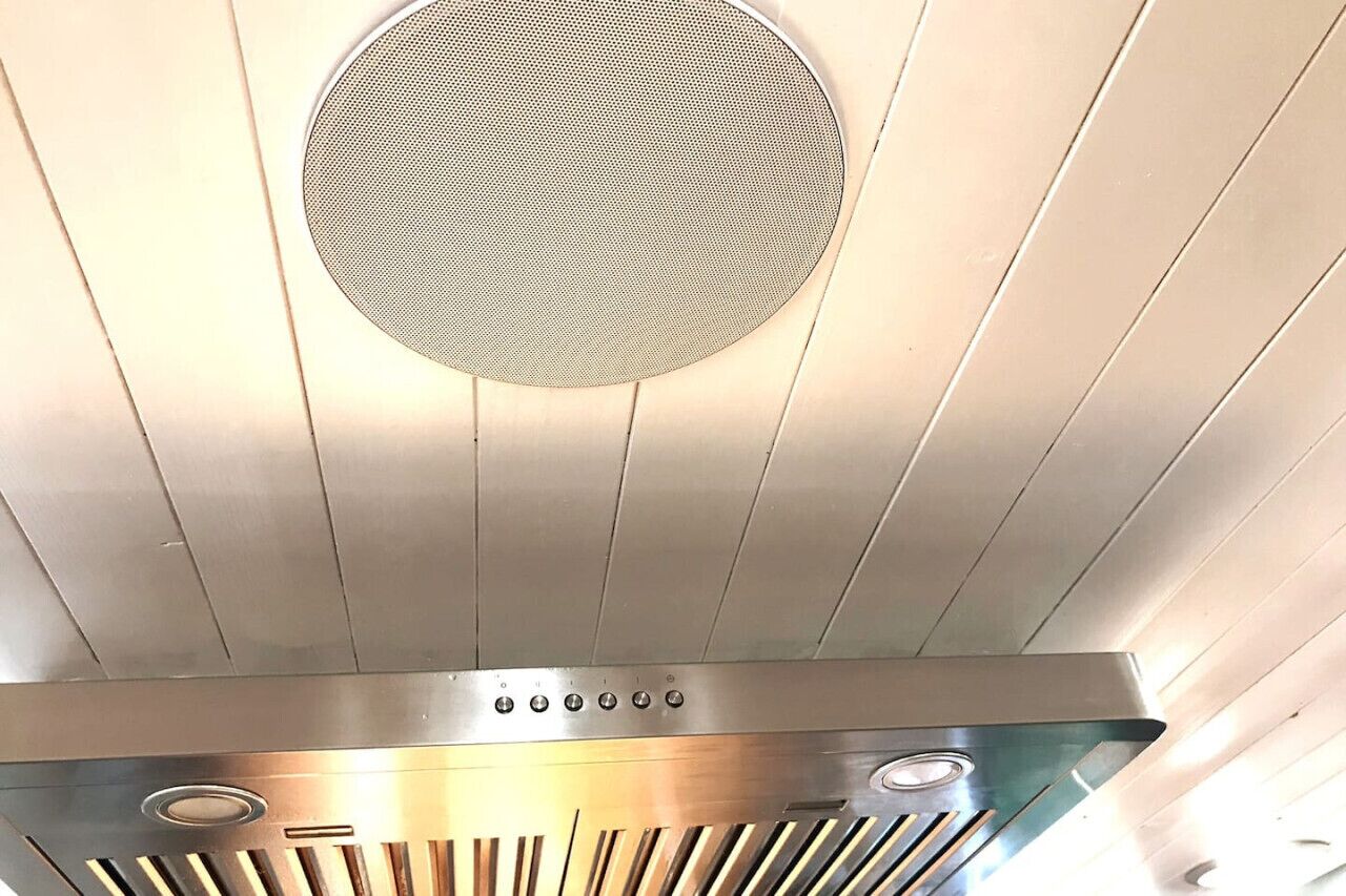 A kitchen with a stainless steel range hood and a circular vent above it.