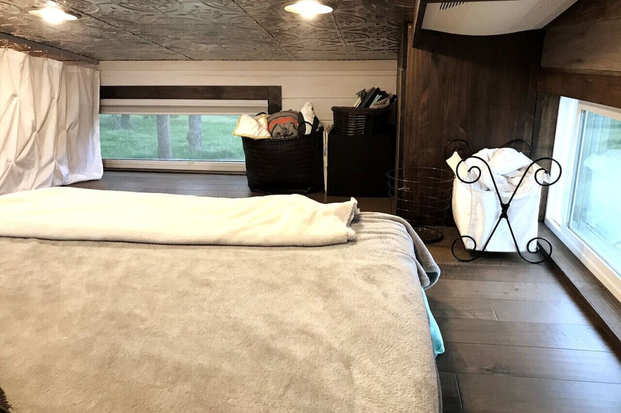Une chambre à coucher avec un lit, une fenêtre, un panier et un présentoir en métal.