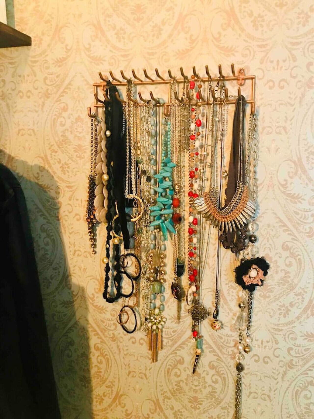 A wall-mounted jewelry rack with various necklaces and bracelets.