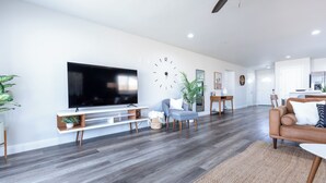 Un salon moderne avec un téléviseur à écran plat, une horloge, un canapé et un coin repas.