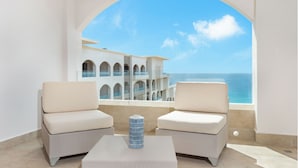 A balcony with two cushioned chairs and a table, overlooking a building with multiple balconies and a view of the sea. - Newer 5 Star Luxurious Resort, Spacious living area and Clean (San José-San Lucas)