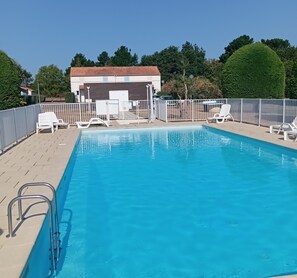 A rectangular swimming pool with a metal ladder on one side, surrounded by a white fence. - Le Green - Piscine - Mer - Wifi (Pornic)