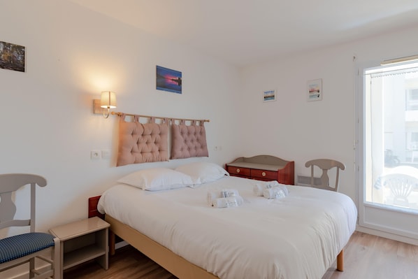 Un dormitorio ordenado con una cama grande, mesitas de noche y un ventanal con vistas.