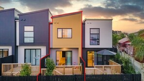 Three connected houses with distinct styles, each with a balcony and sliding door, offering a relaxing outdoor space.