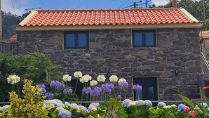 A two-story stone house with a red-tiled roof and two windows. - Recanto das Florenças (3) – Stone House (Arco da Calheta)