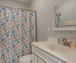 Een bad/douchecombinatie, een haardroger, handdoeken, zeep