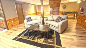 A room with two sofas, a coffee table, a wooden floor, and a foosball table. - Vacation at a family & pet friendly cabin in the Blue Ridge mountains! (Murphy)
