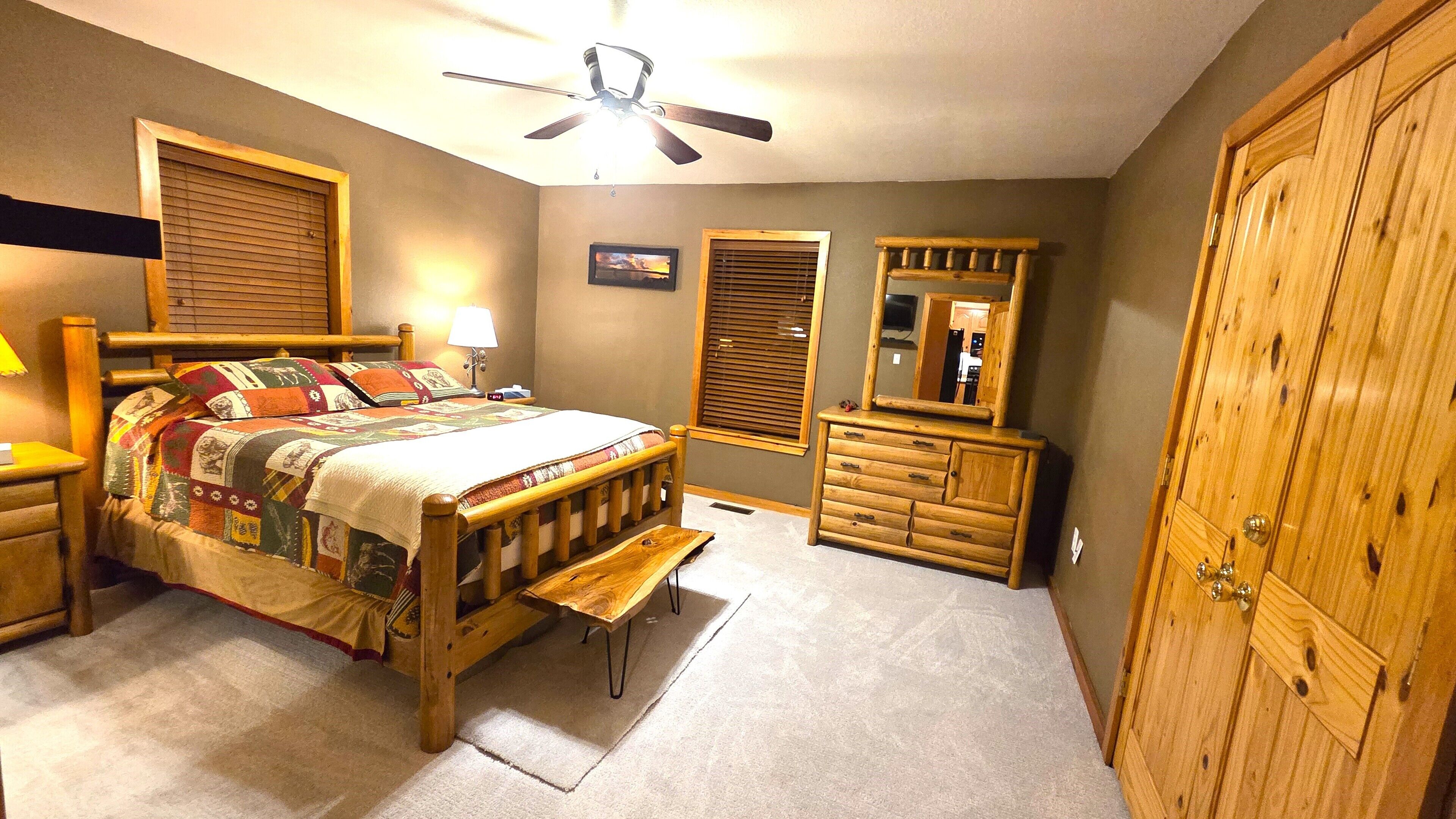 Une chambre à coucher comprenant un lit, un banc en bois, une commode, un miroir et une armoire.