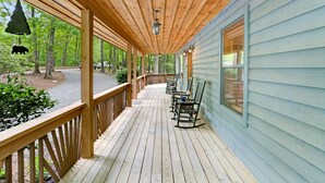 A wooden deck with outdoor seating, a hanging bell, and a view of the surrounding forest. - Vacation at a family & pet friendly cabin in the Blue Ridge mountains! (Murphy)