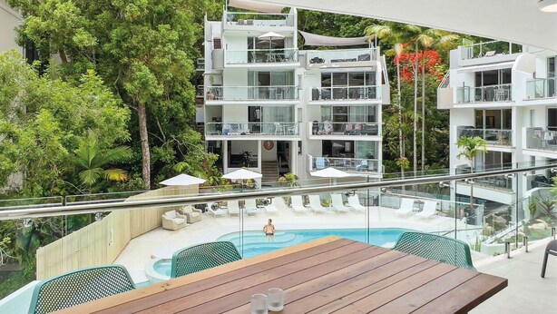 Un hôtel moderne doté d’une piscine, d’un espace extérieur aménagé et d’une végétation luxuriante.
