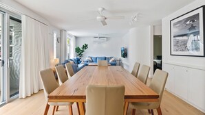 Une salle à manger moderne avec une table et des chaises en bois, un canapé bleu et un ventilateur de plafond.