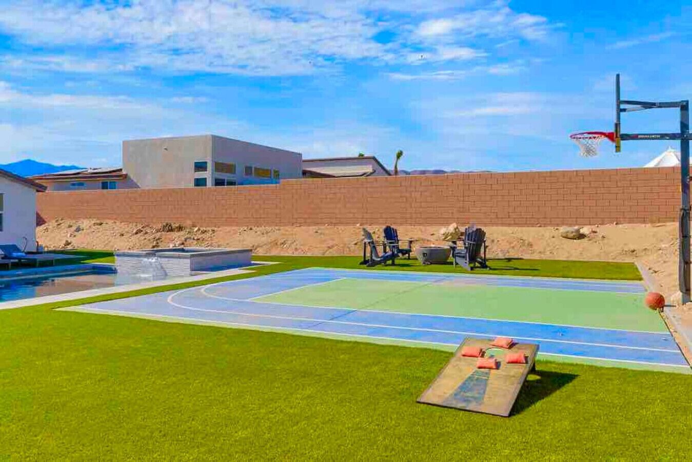 Un terrain de basketball en plein air avec une piscine et des chaises longues.
