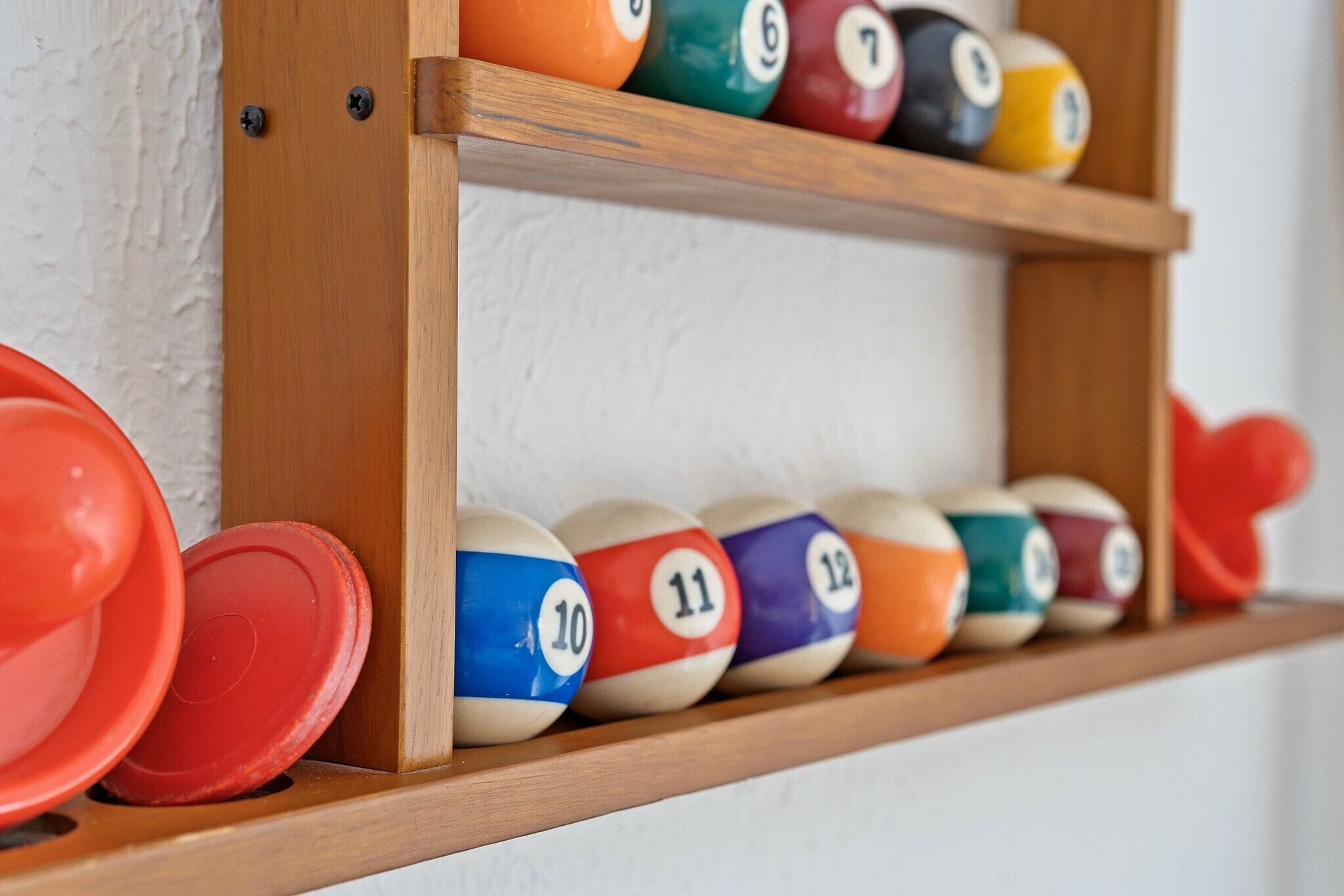 A wooden shelf with numbered billiard balls and a red cue ball.
