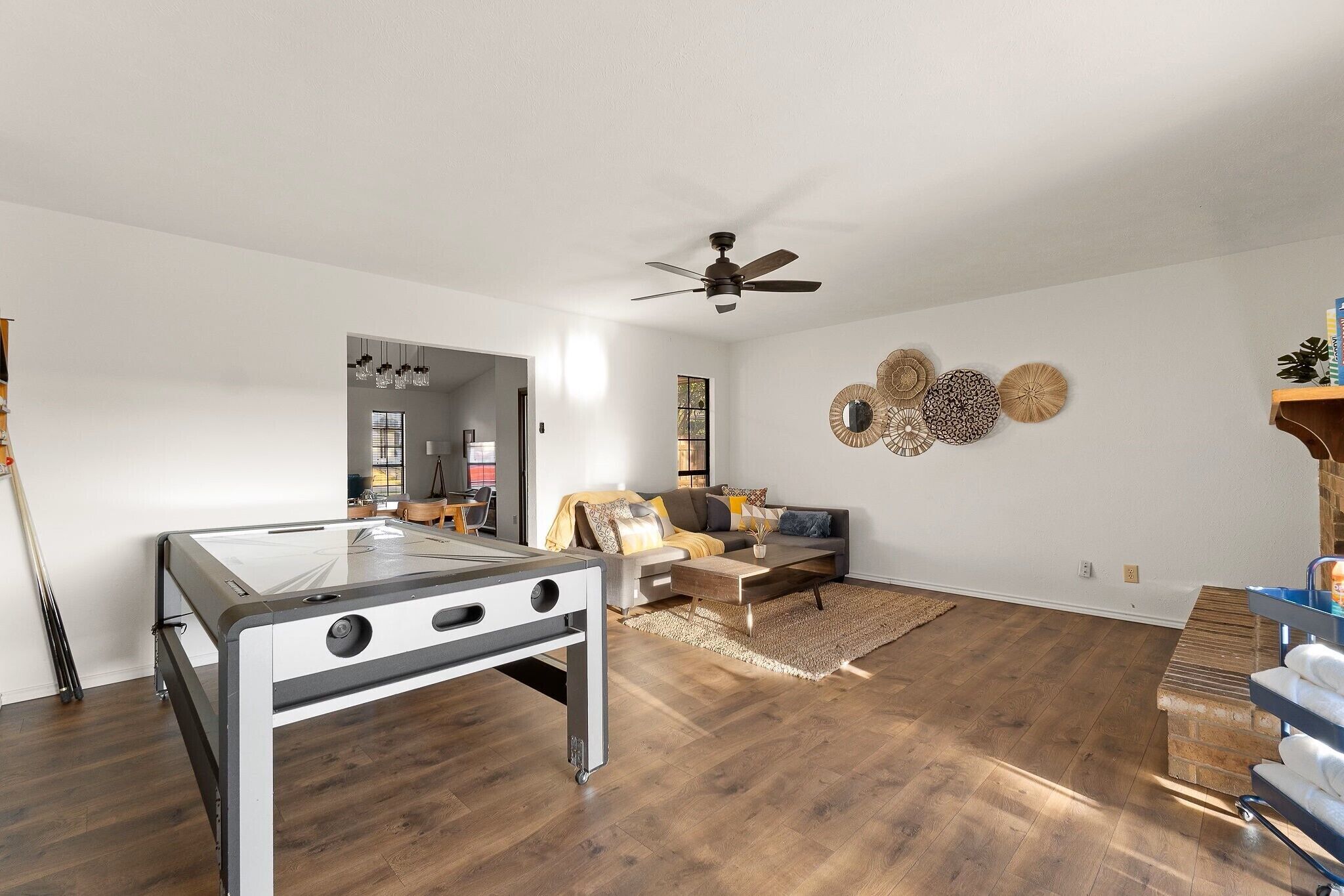 A spacious living room with a glass-top table, a ceiling fan, a sofa, and a coffee table.
