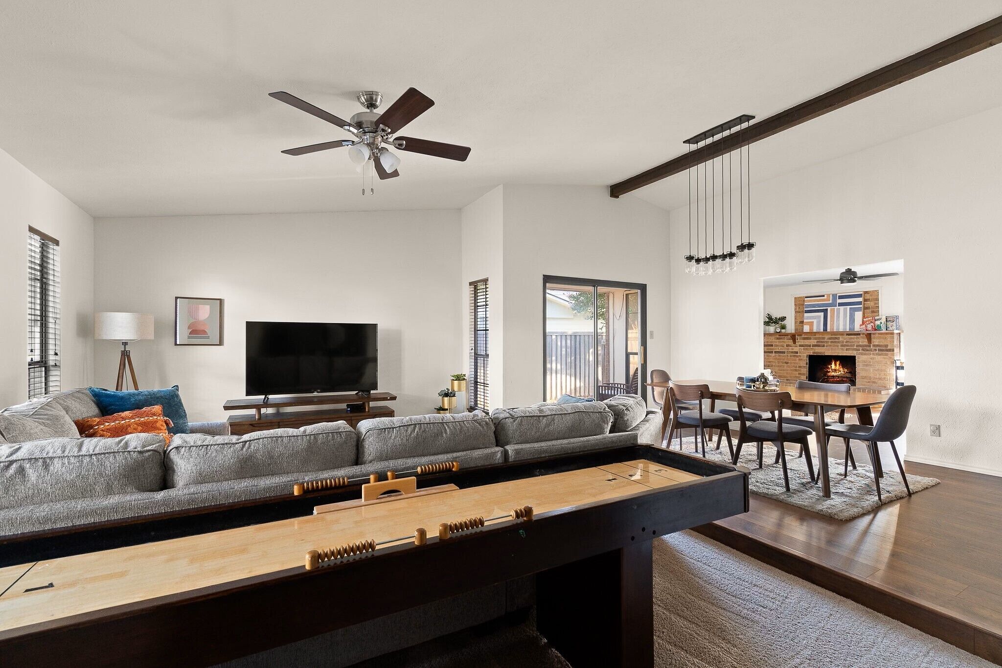 Una sala de estar moderna con sofá, televisor y mesa de futbolín.