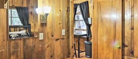 Una habitación de madera con una cama, un escritorio y una ventana con cortinas.