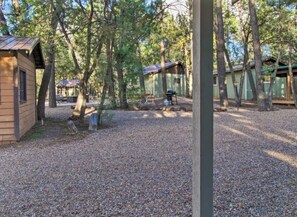 A campground with multiple cabins, gravel ground, and trees. - Cabin 9 — King Cabin with Private Indoor Hot Tub (Lakeside)