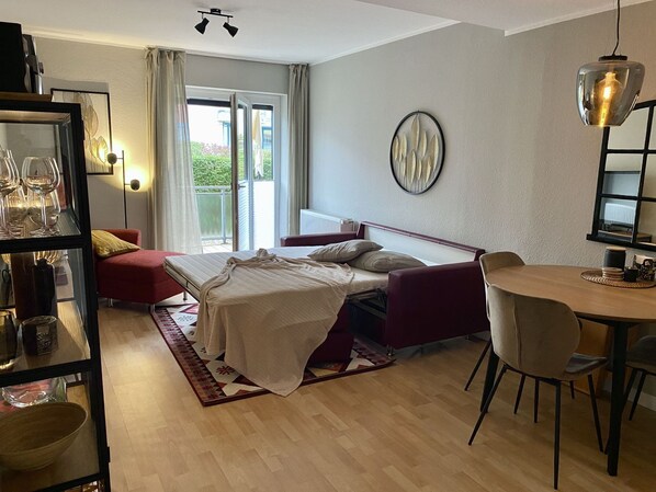 A modern bedroom with a bed, a desk, and a dining area.