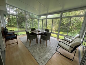 Relax in this spacious sunroom with a dining table, wicker chairs, and a cushioned bench.