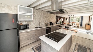 Une cuisine moderne dotée d’un grand îlot central, d’un four à micro-ondes encastré et d’appareils électroménagers en acier inoxydable.