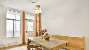 A dining area with a wooden table, bench, and a vase with flowers. - La Maison Du Mile-End (Montreal)