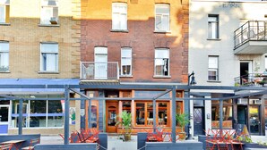 A row of three-story brick buildings with a café in the center. - La Maison Du Mile-End (Montreal)