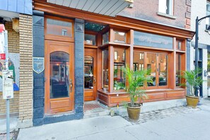 A brick building with large windows and a wooden facade. - La Maison Du Mile-End (Montreal)