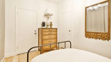A bedroom with a bed, a wooden dresser, a mirror, and a chandelier.