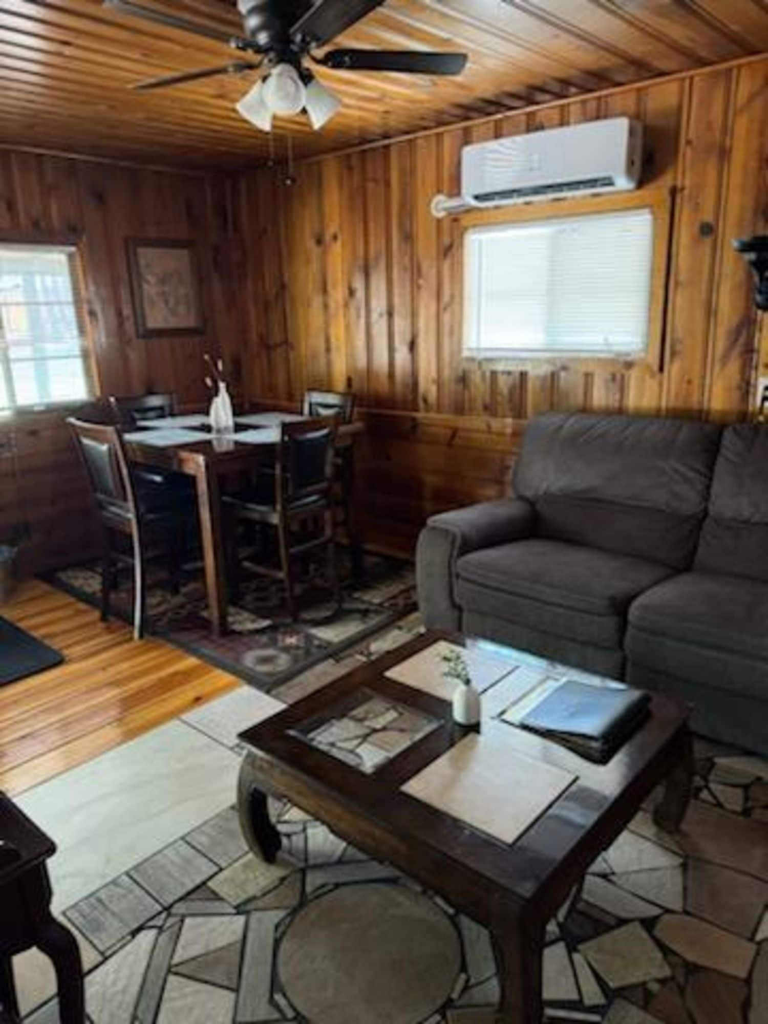 A wooden interior with a dining area, a sofa, and a ceiling fan.
